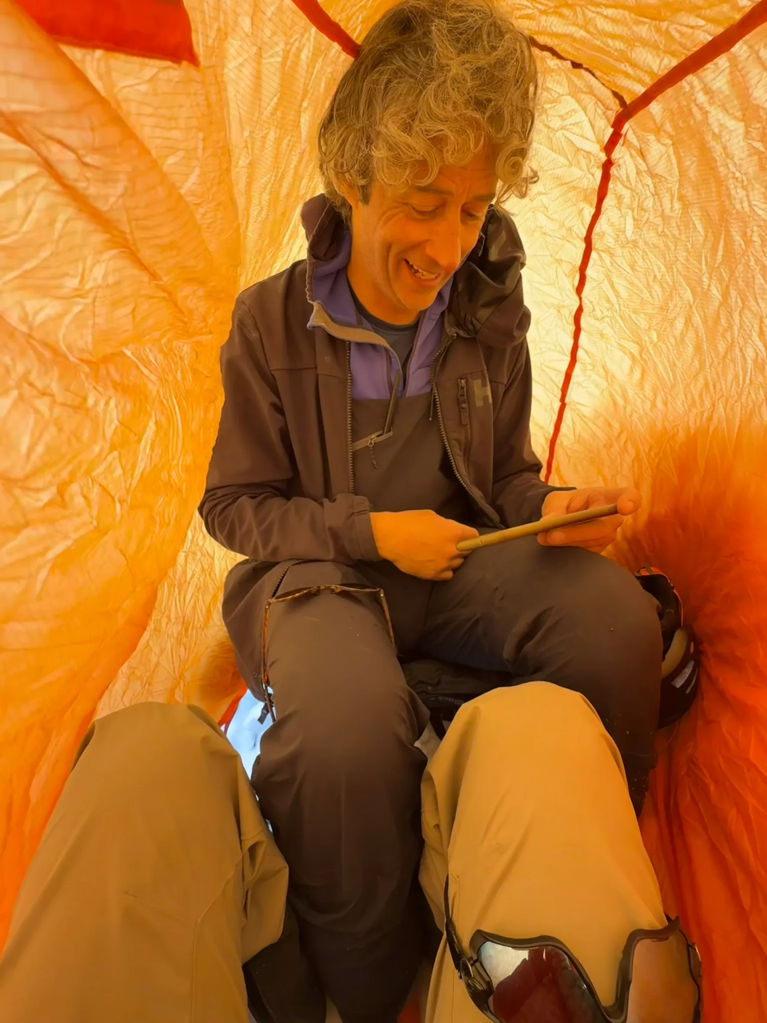 Chris seated inside an orange bothy bag while waiting out the storm