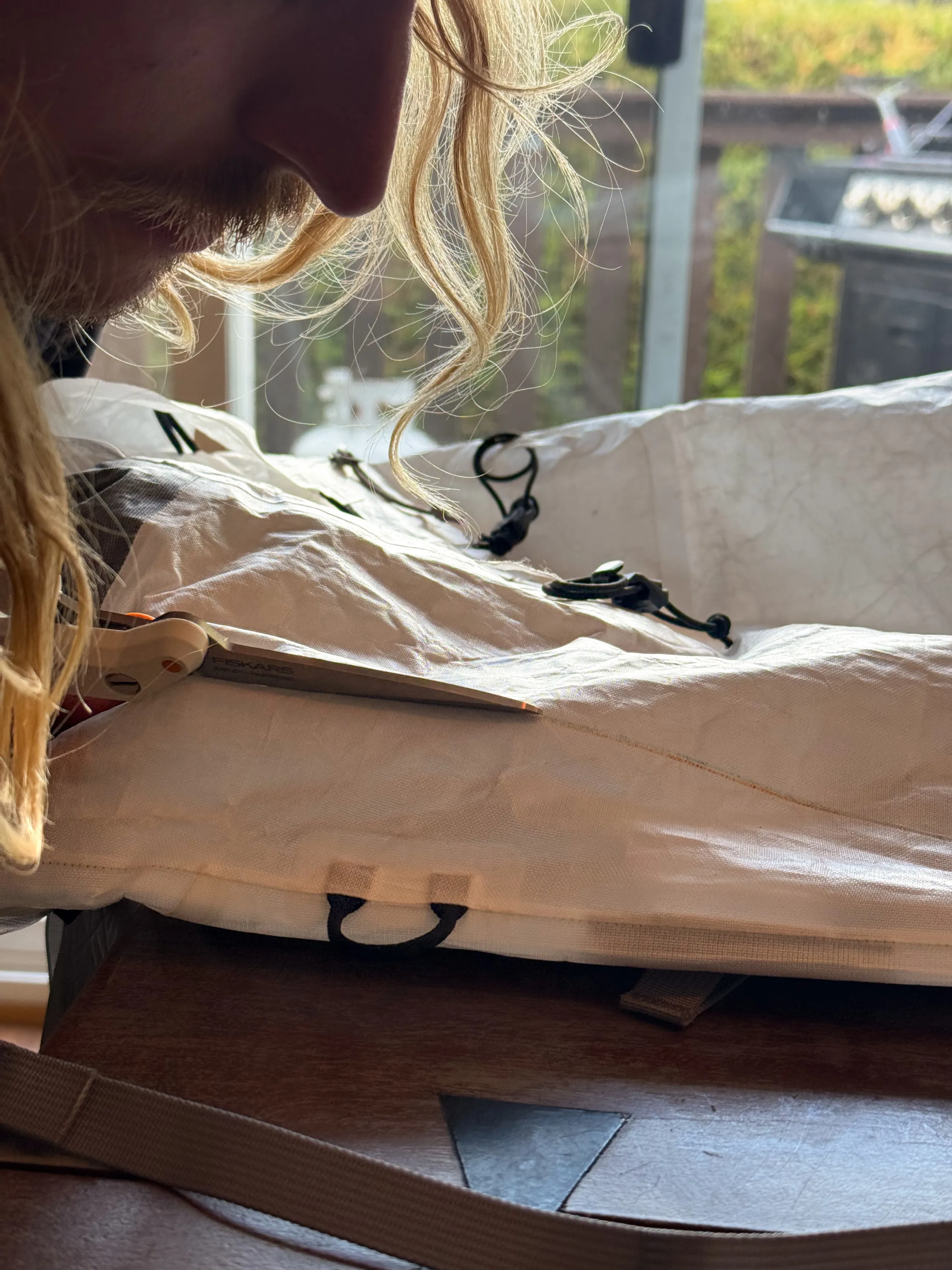 James cutting the rectangular side opening into the white ALUULA body of an Arc'teryx Alpha SL 30