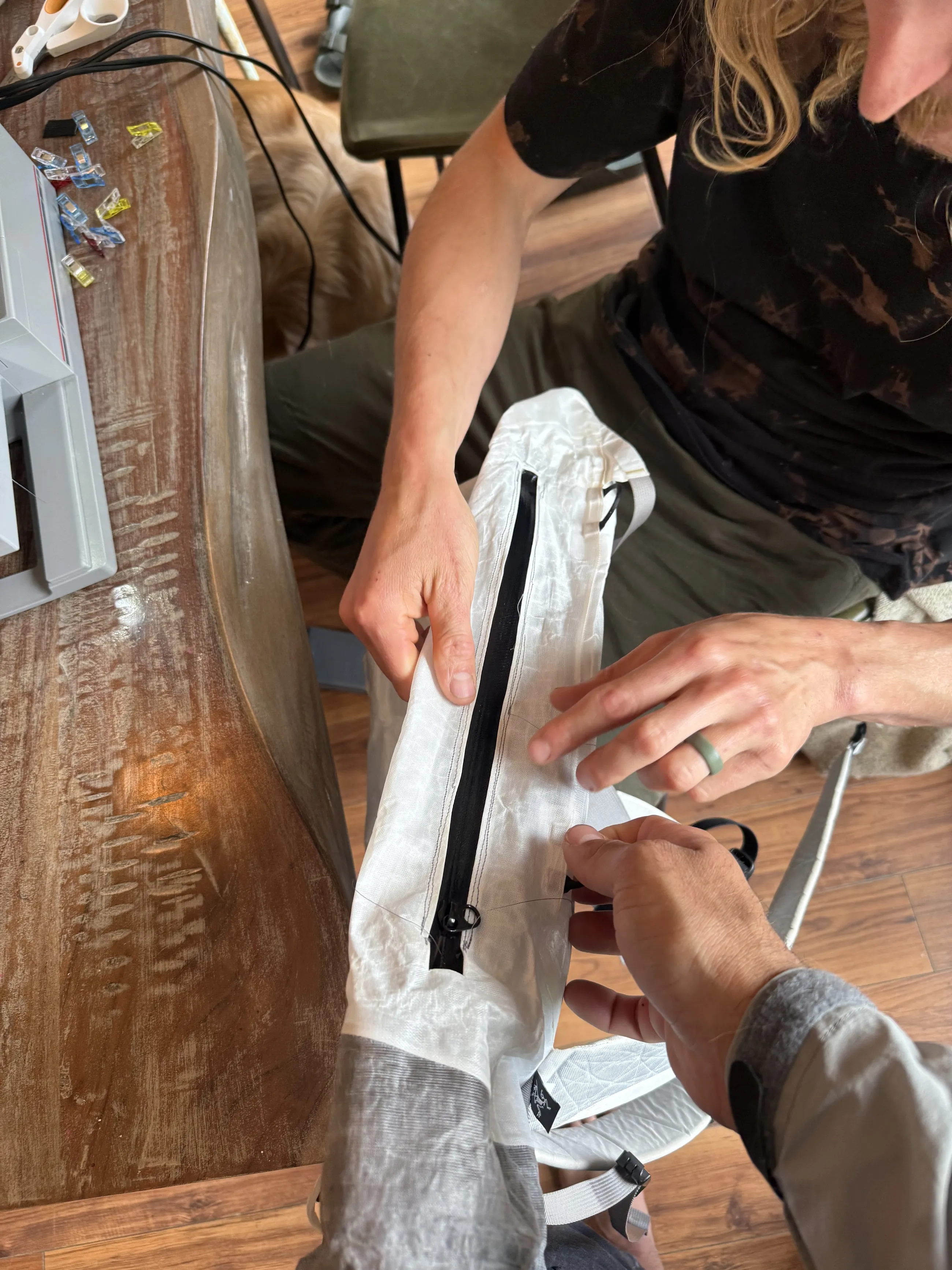 Hands aligning the stitched side zipper and reinforced ALUULA edge on the Alpha SL 30