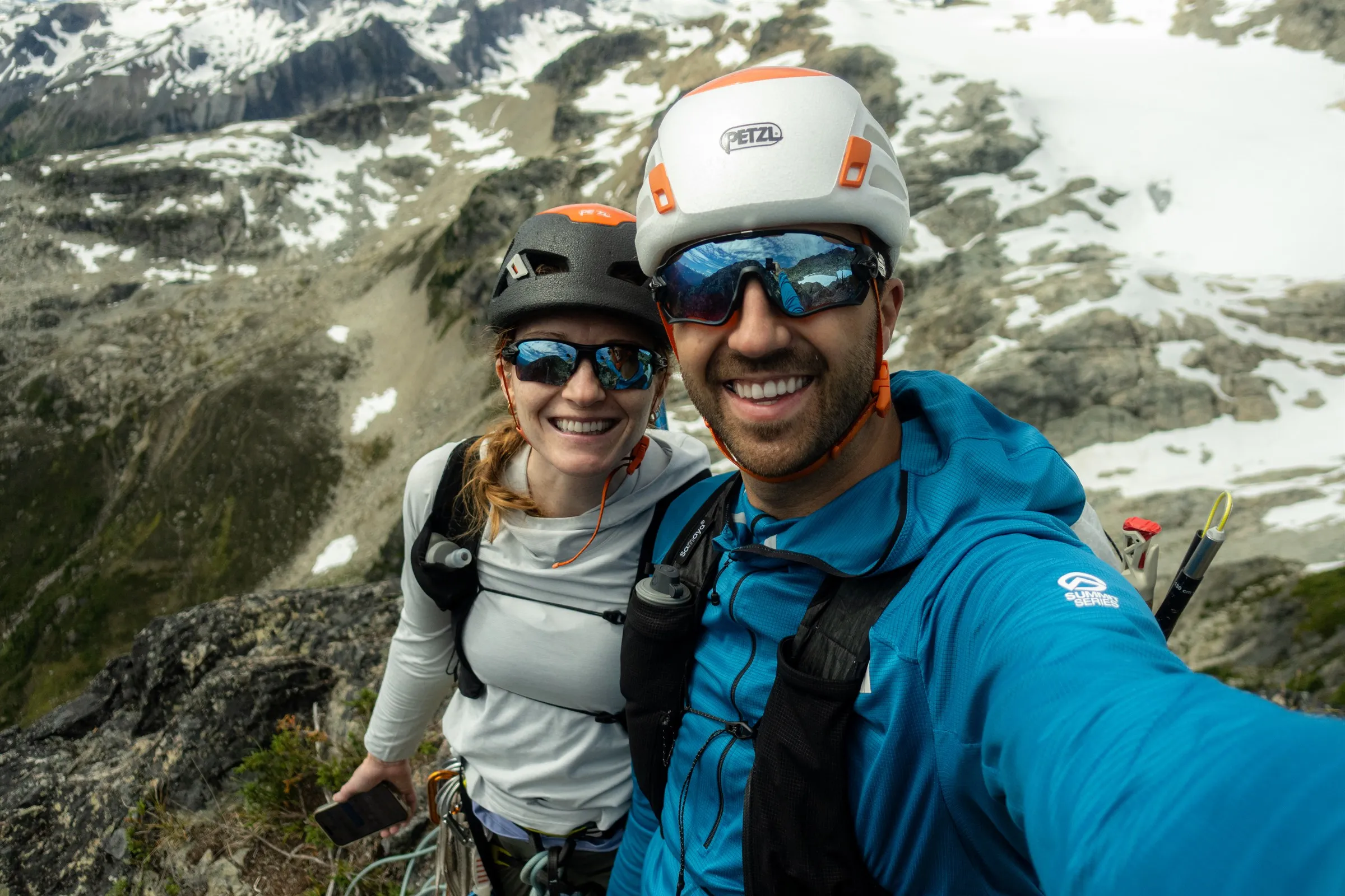 Jordan and Linsey smiling together in climbing helmets at the top of Bastardo
