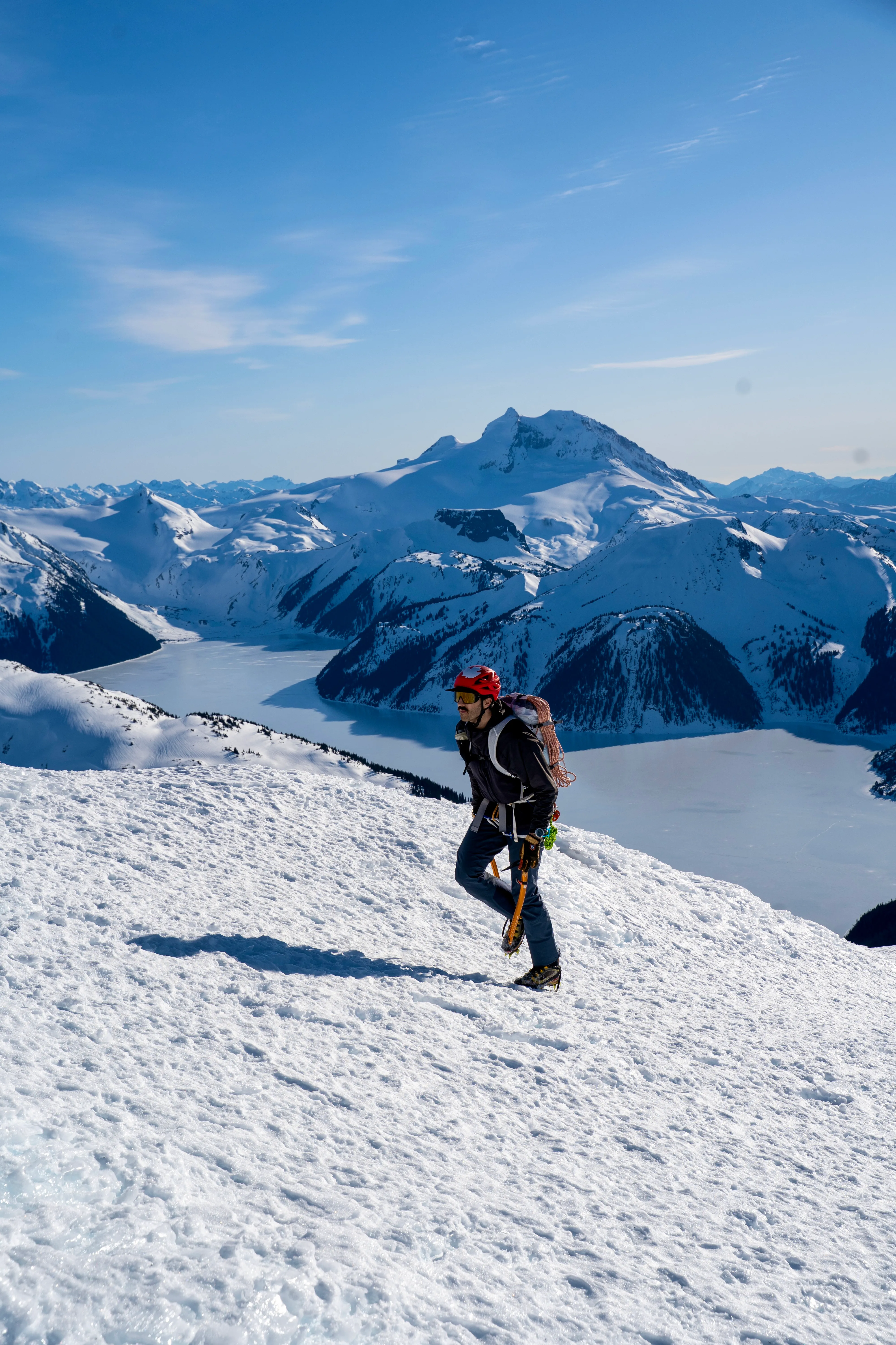 Jordan Lovis climbing a snowy alpine slope above frozen lakes in the Coast Mountains