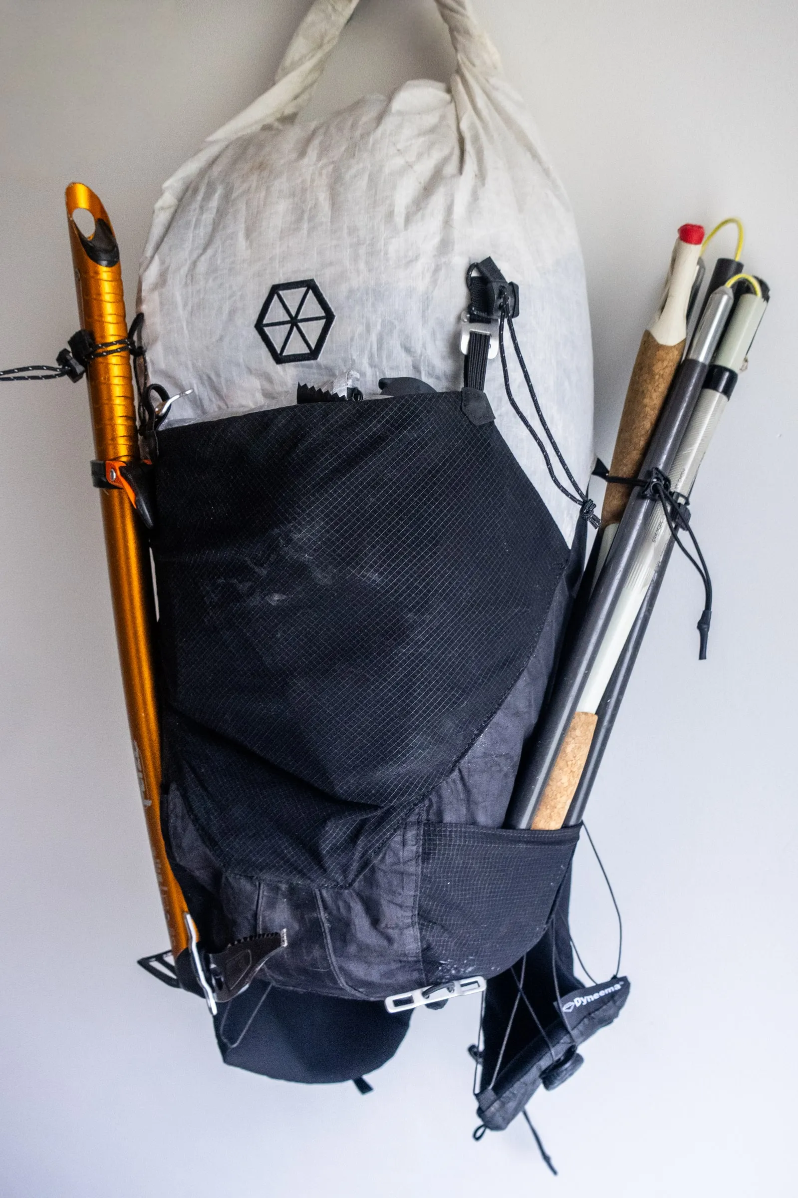 Folded trekking poles secured in the side sleeve and upper cord of the Samaya Ultra Pace