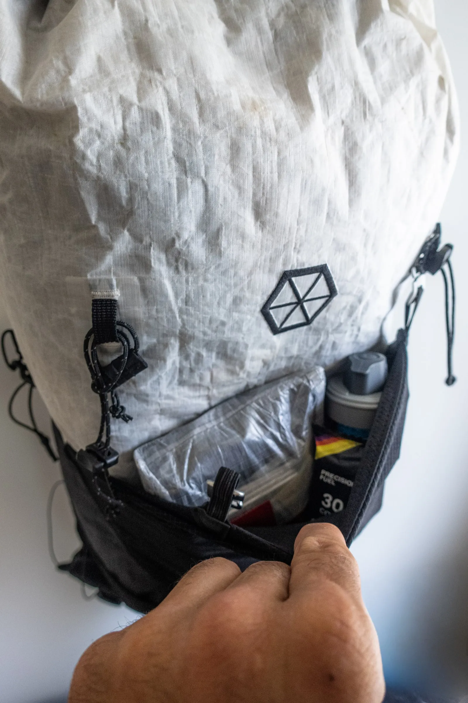 Open rear stretch pocket on the Samaya Ultra Pace holding a first-aid kit, headlamp, gels, water filter, and snacks