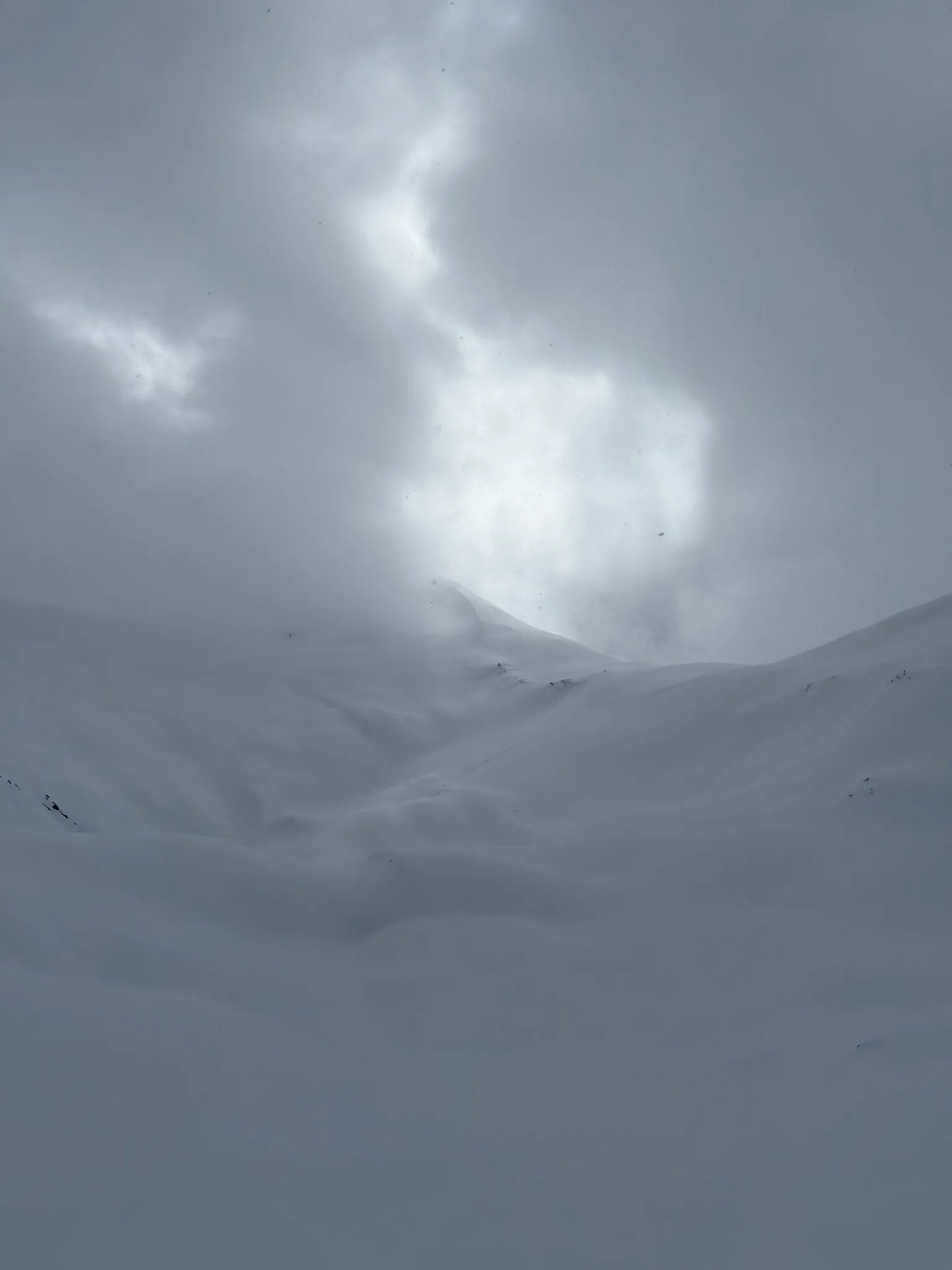 The unnamed summit briefly visible through clouds closing over the alpine bowl near Azure Pass