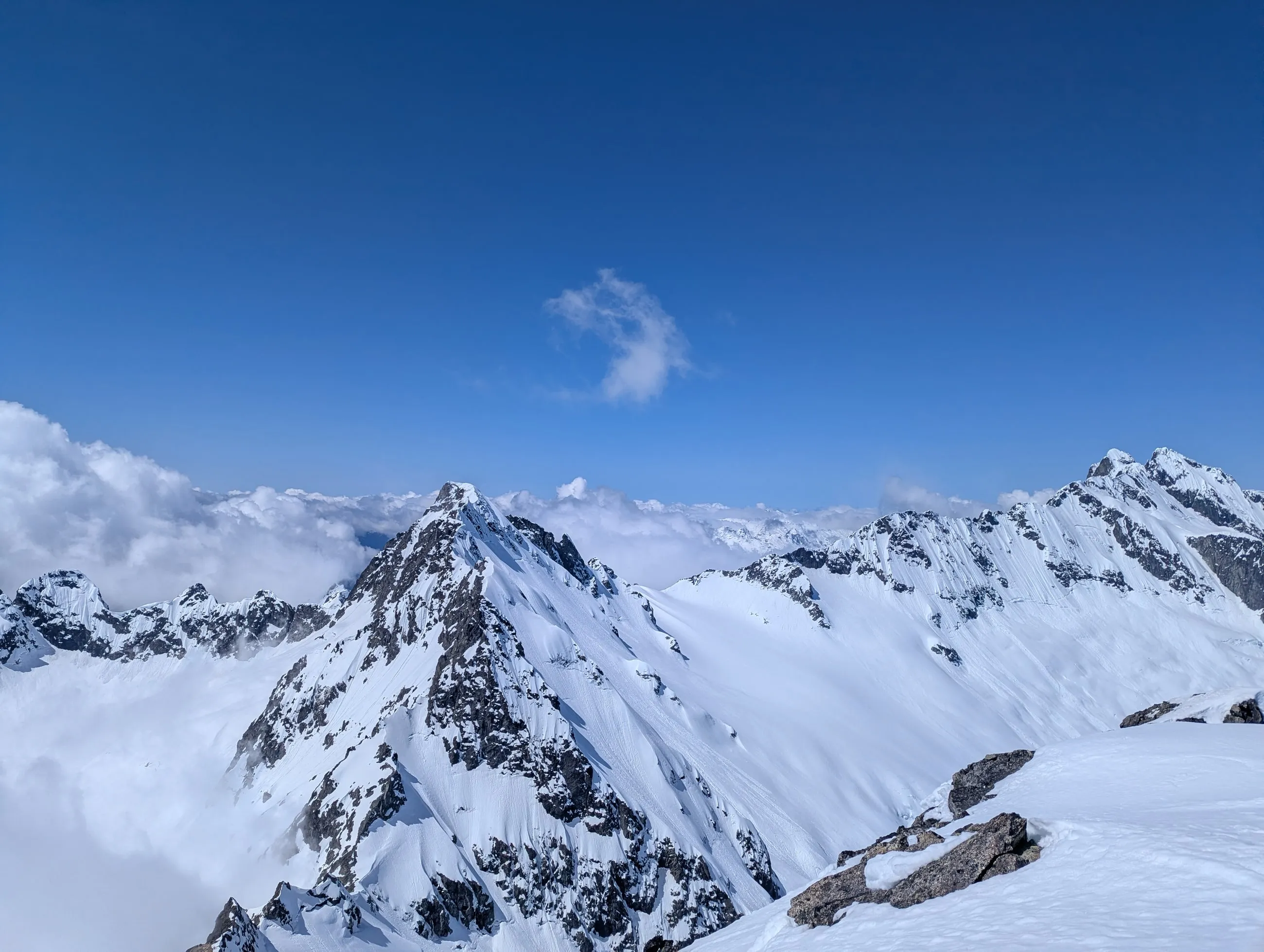 Serratus and the surrounding Tantalus peaks rising above clouds from the summit of Alpha