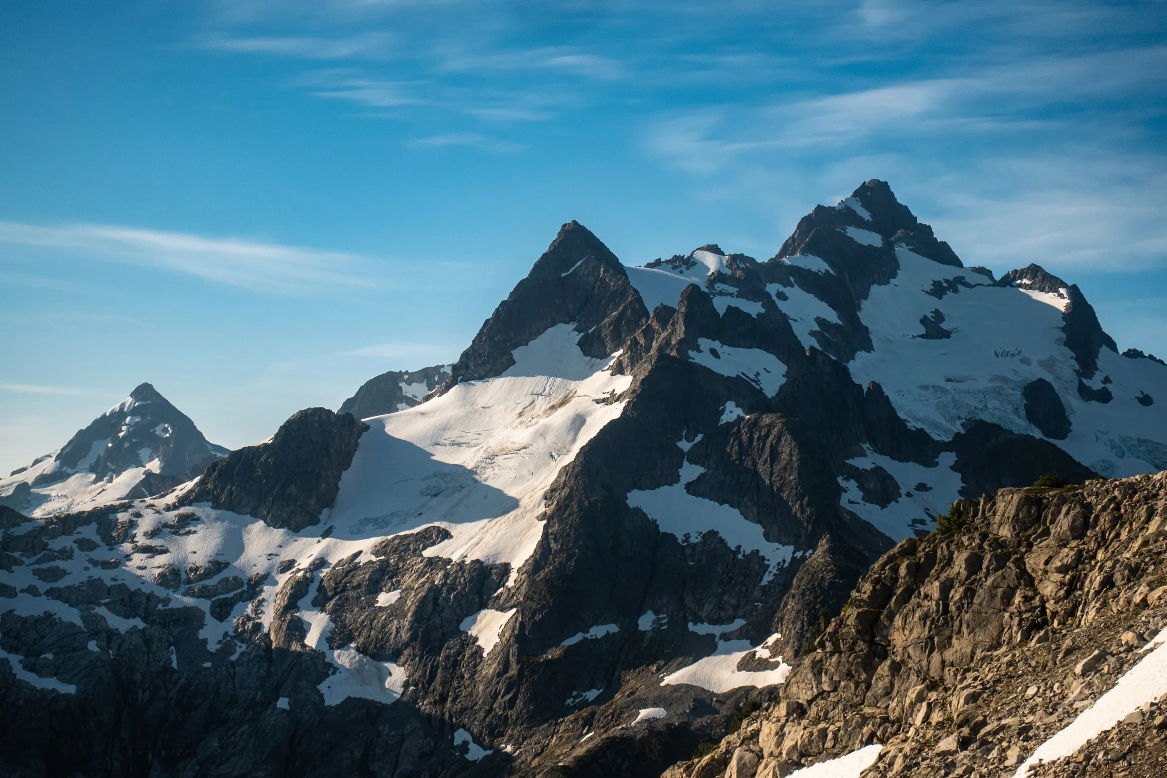 Glaciated peaks and dark rock rising beneath a blue sky in the Tantalus Range