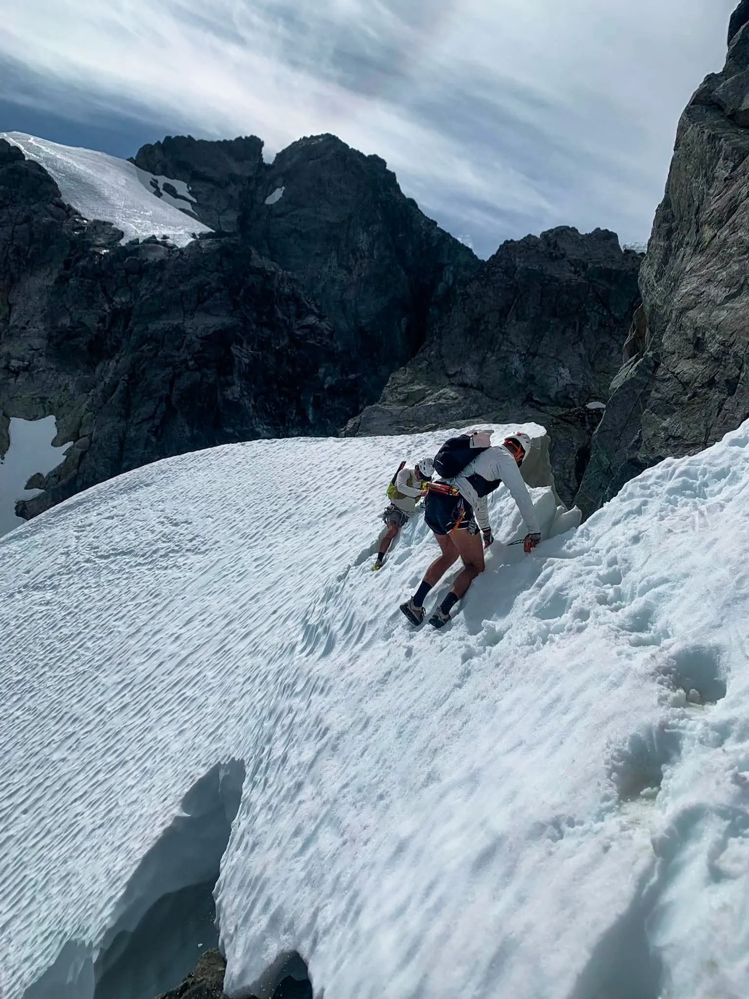 Jordan in crampons crossing a steep snow bridge to gain the summit ridge of Mount Tantalus