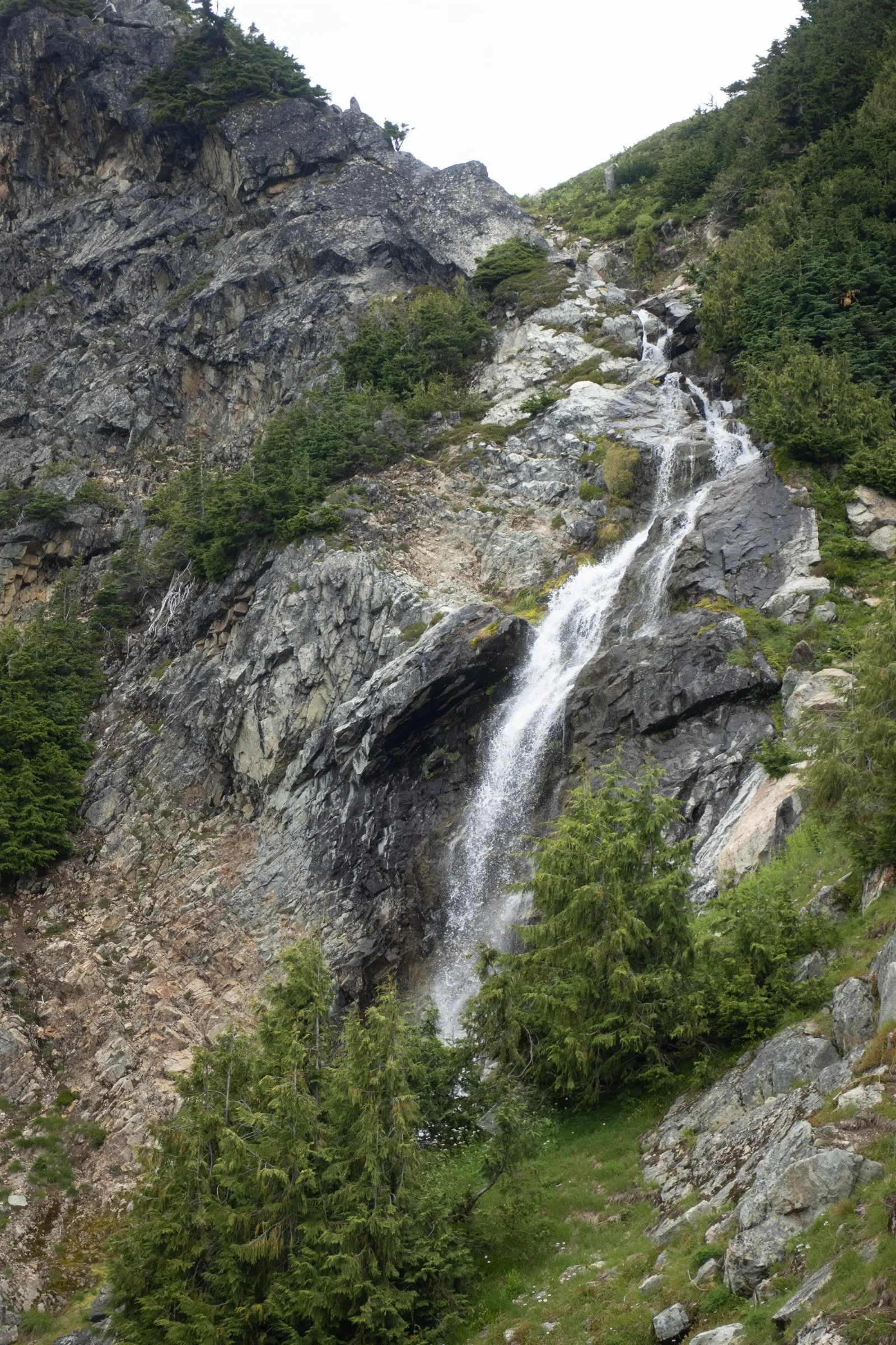 A waterfall cascading through dark rock and trees beside the upper approach to Bastardo